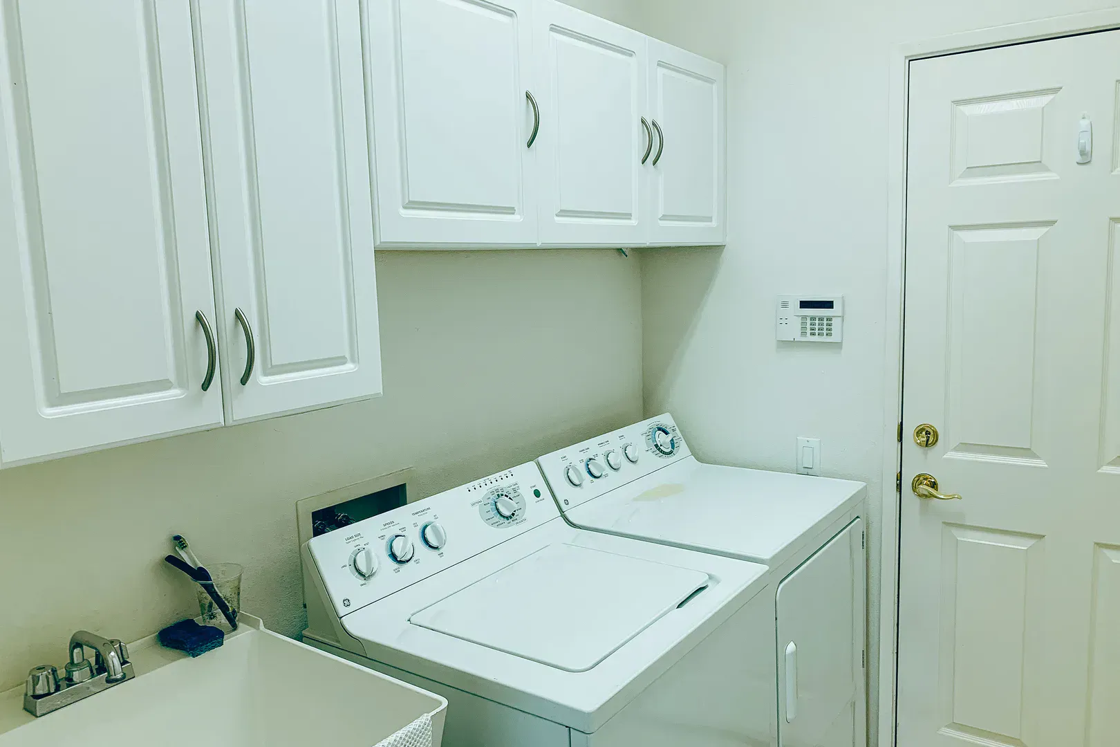 Tidy laundry room with washer, dryer, and white cabinets, the kind of setup that earns a yearly vent cleaning