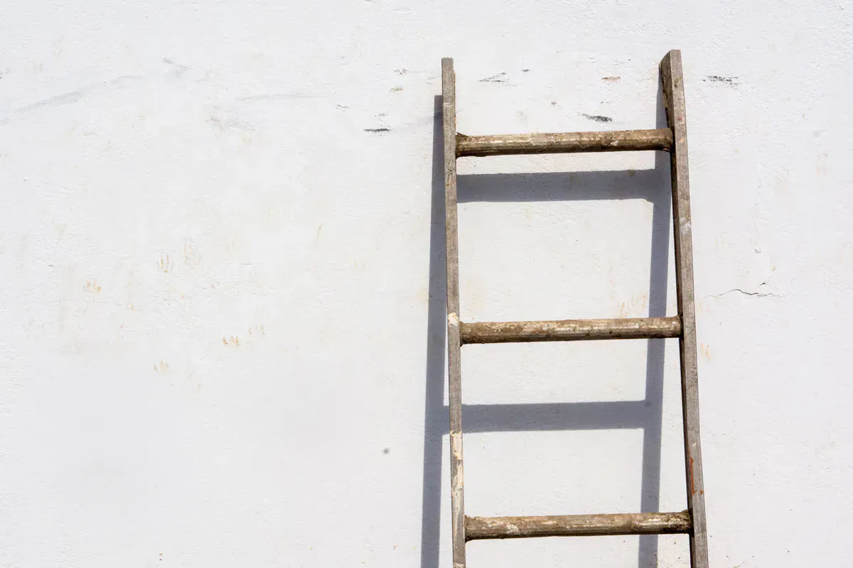 Ladder leaning bare against a house wall with no standoff bar, the setup a stabilizer is built to fix