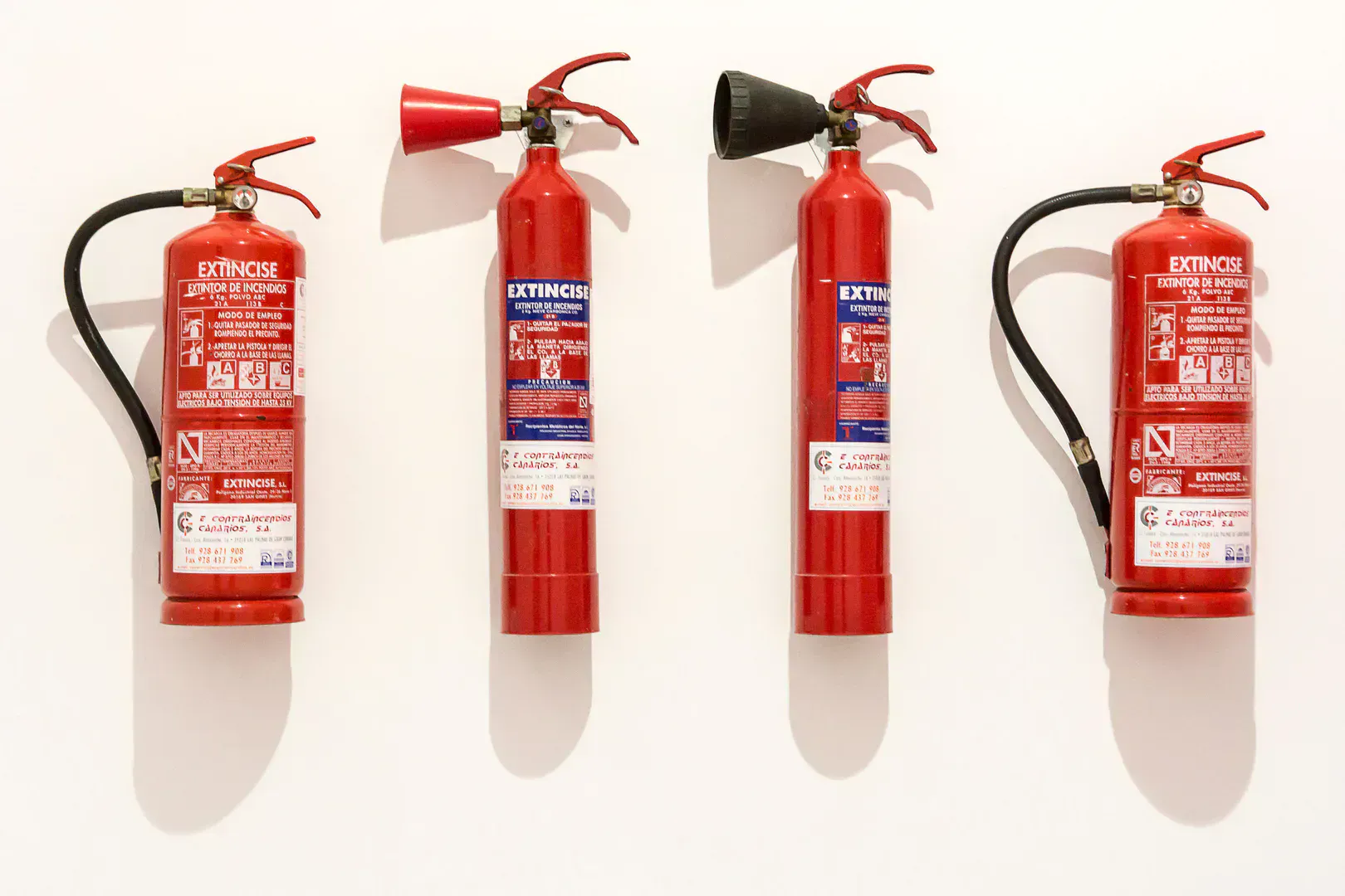 Fire extinguishers mounted in a row on a white wall