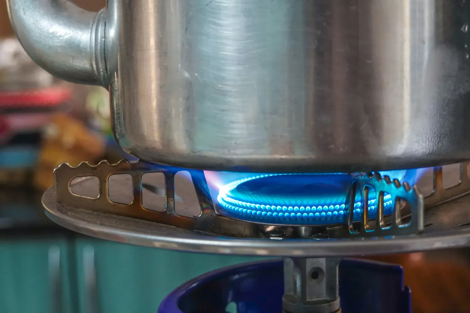 Blue gas flame under a metal pot on a home stove, the small contained cooktop fire a kitchen fire blanket is built to smother