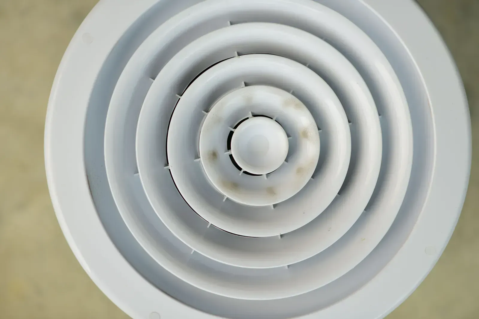White circular supply air vent up close, where filtered air re-enters the room