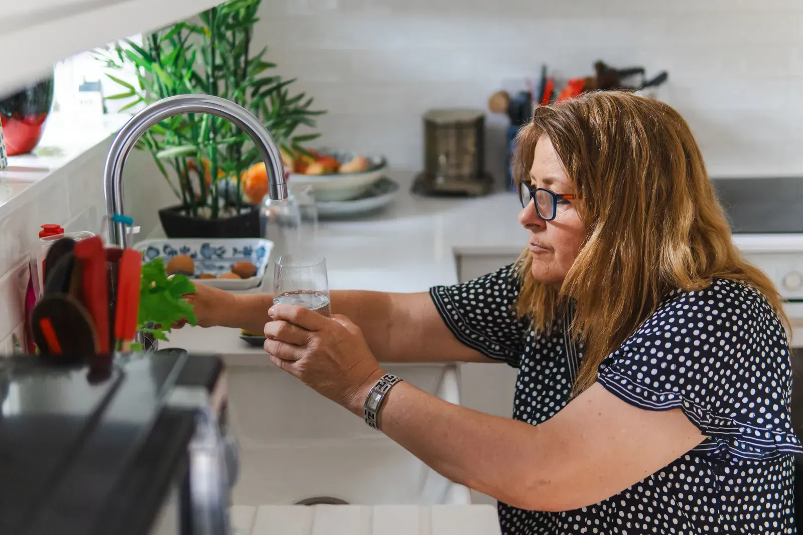 Filling a drinking glass at a kitchen counter