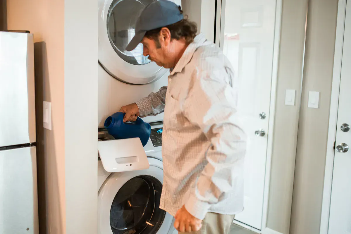Man starting a load on a stacked washer and dryer at home