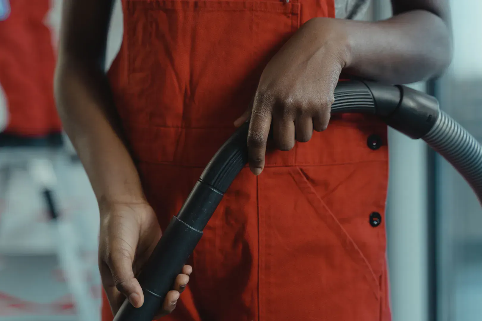 Homeowner holding a vacuum hose, the base tool that skinny lint attachments snap onto for dryer cleaning