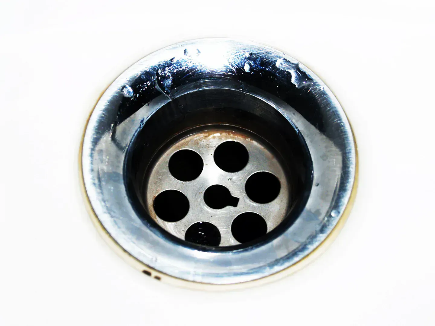 Chrome sink drain with water droplets, the connection that drips into the cabinet long before anyone notices